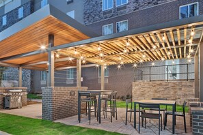 An outdoor patio area with a grill, seating, and string lights. - Candlewood Suites Newnan - Atlanta SW by IHG (Newnan)