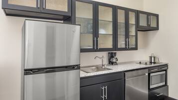 Una cocina con un refrigerador de acero inoxidable, una cafetera y un microondas.