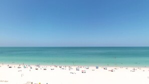 Une plage à l’eau turquoise et limpide, bordée d’un rivage sablonneux.