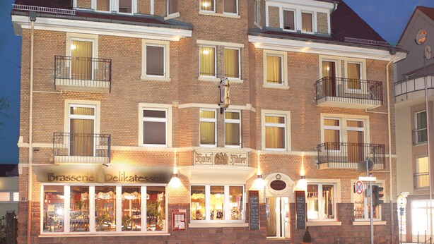 A multi-story hotel with a brick facade, multiple balconies, and a ground-level restaurant. - Hotel-Events Adlerpalast (Ruesselsheim)