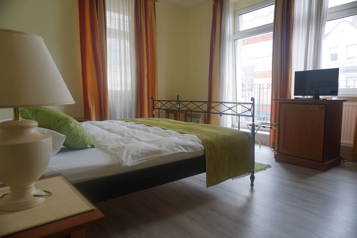Une chambre d’hôtel avec un lit, une télévision, une lampe et des rideaux.
