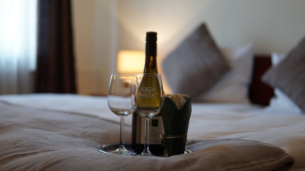 Un lit avec une bouteille de vin et deux verres dessus.