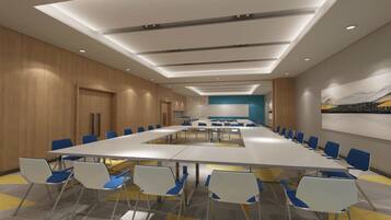 Un salón de conferencias con una larga mesa y sillas, paredes de paneles de madera e iluminación empotrada en el techo.