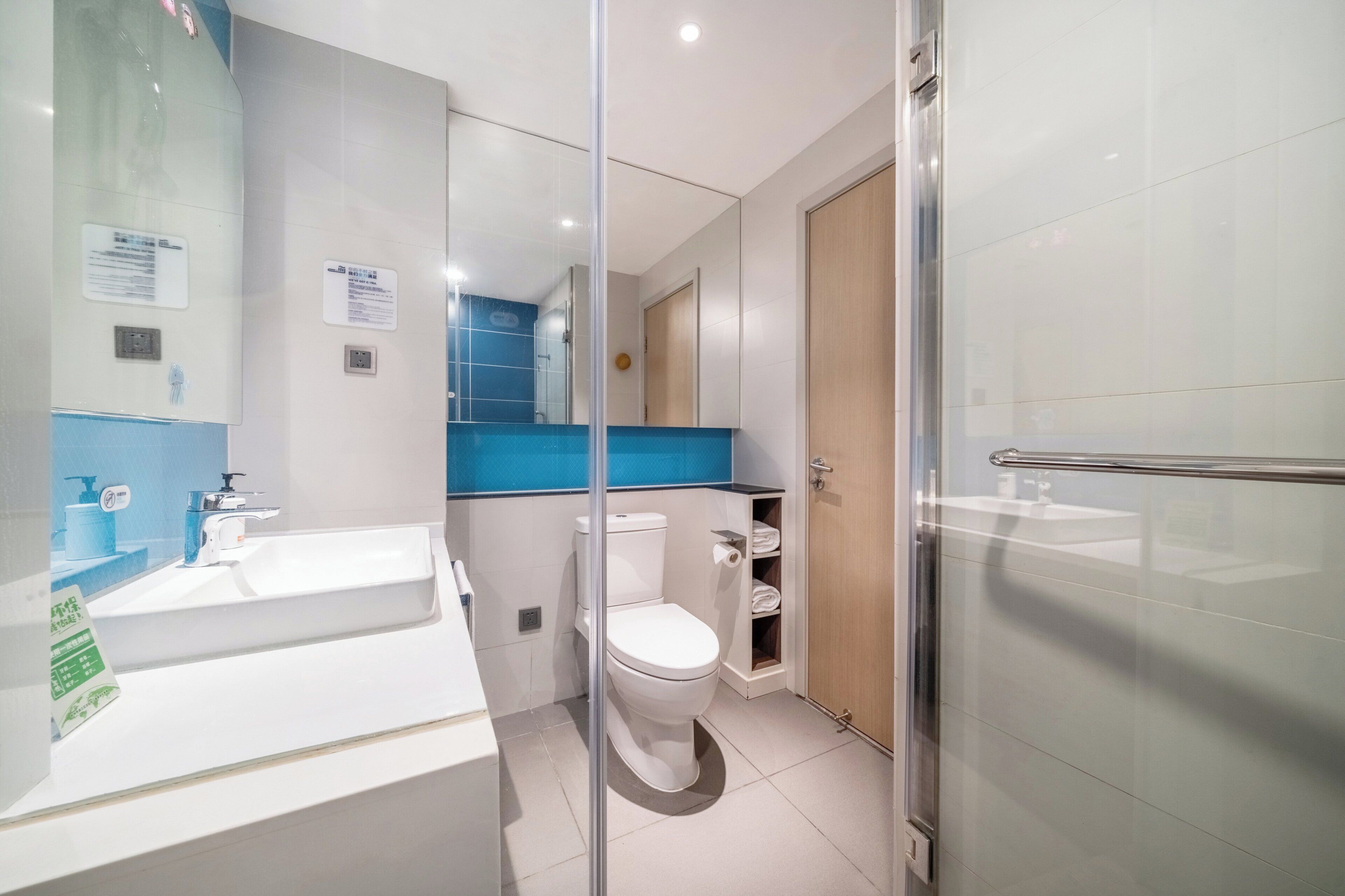 A modern bathroom with a white sink, a toilet, and a glass shower enclosure.