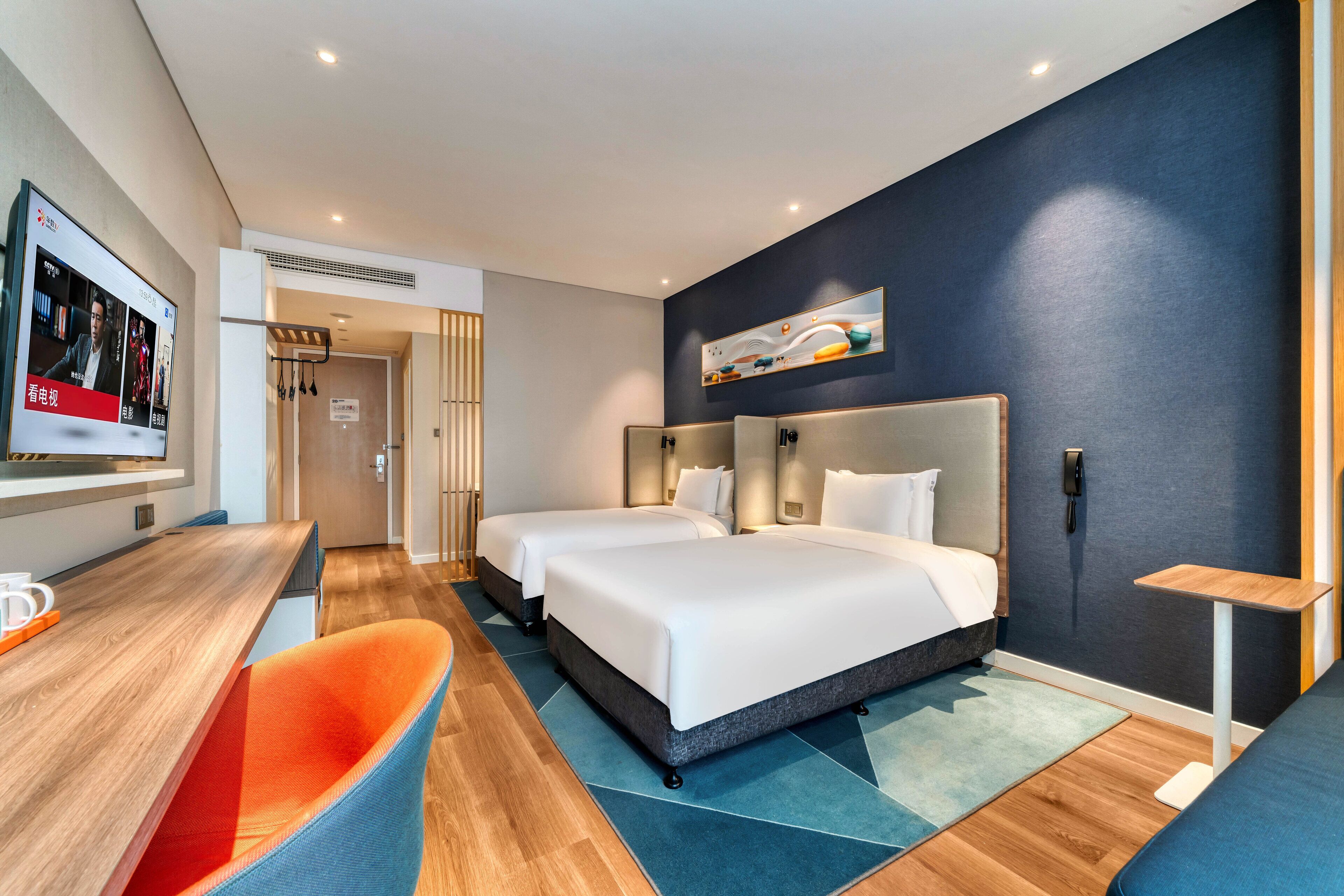 A modern hotel room with two beds, a desk, and a chair.