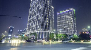 Un edificio de gran altura con fachada enrejada y ventanas iluminadas durante la noche.