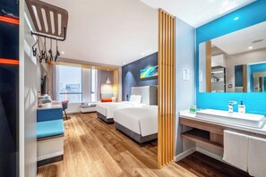 A modern hotel room with a large bed, a desk, a chair, a bathroom with a sink and mirror, and a view of the city. - Holiday Inn Express Hangzhou Binjiang by IHG (Hangzhou)