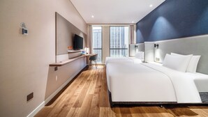 A modern hotel room with a large bed, a TV, a desk, and a view of the city through large windows. - Holiday Inn Express Hangzhou Binjiang by IHG (Hangzhou)