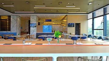 Um restaurante moderno com paredes de mármore, um balcão comprido e cadeiras azuis.