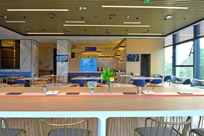 Un restaurante moderno con paredes de mármol, una barra alargada y sillas azules.