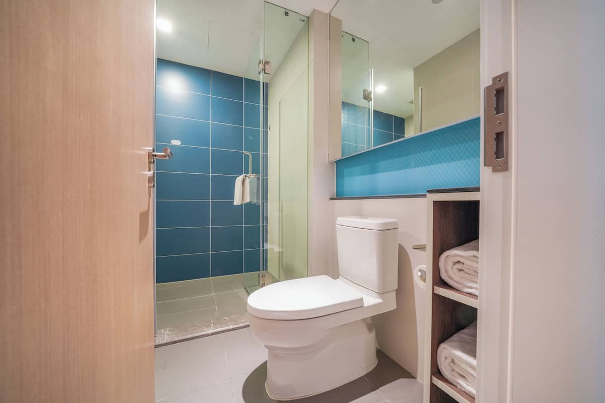 A bathroom with a toilet, a glass shower enclosure, and a towel rack.