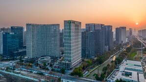 A high-rise urban building complex with multiple skyscrapers, a central tower with a grid-like facade, and a surrounding area with roads and greenery. - Holiday Inn Express Hangzhou Binjiang by IHG (Hangzhou)