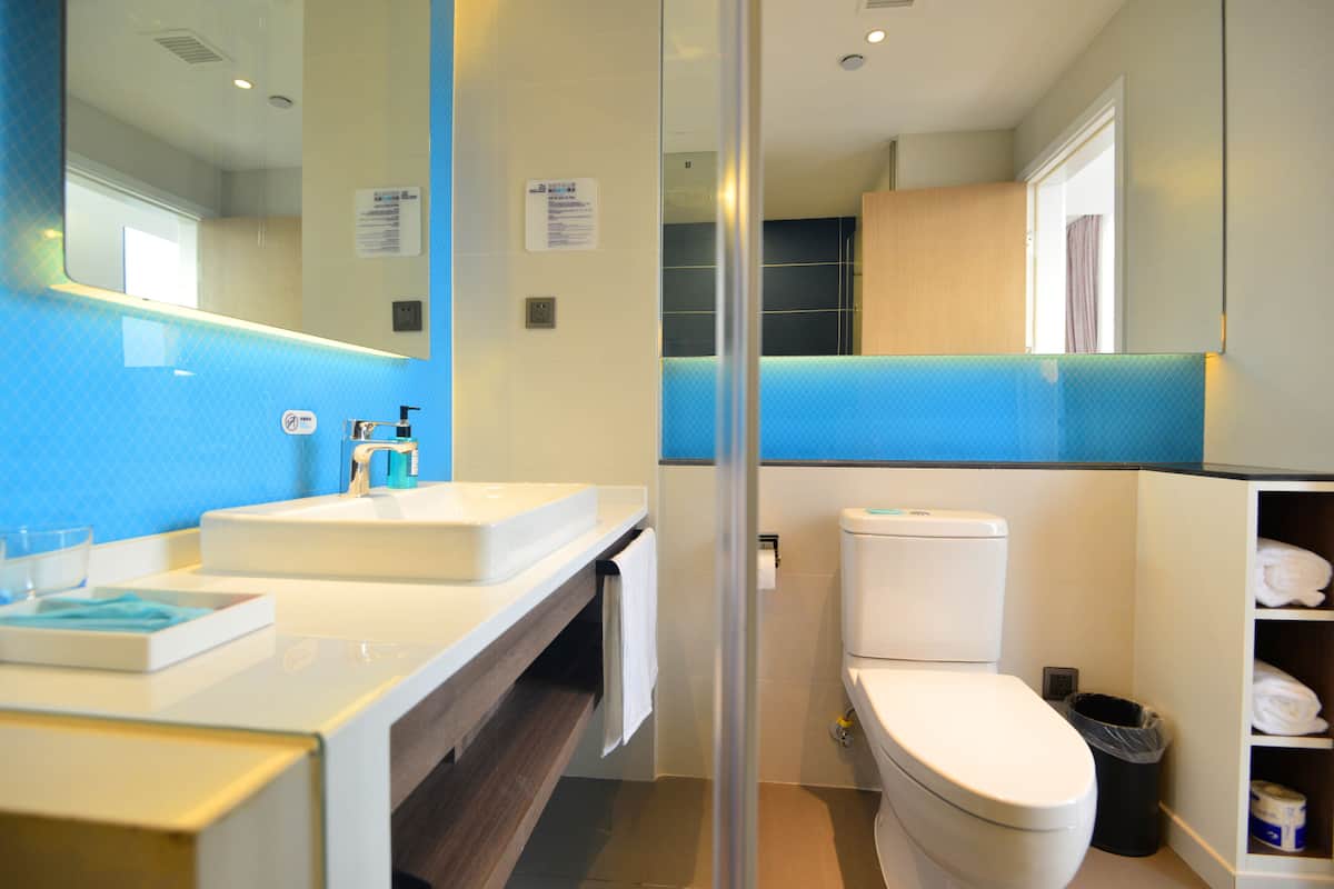 A modern bathroom with a white sink, a mirror, a toilet, and a glass shower enclosure.