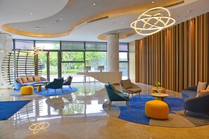 A modern lobby with seating areas, a reception desk, and large windows offering a view of greenery. - Holiday Inn Express Hangzhou Binjiang by IHG (Hangzhou)