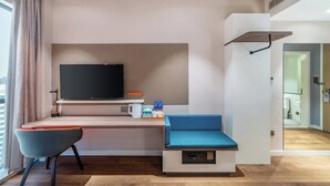 A modern hotel room with a flat-screen TV, a desk with a chair, a small seating area, and a view of the city. - Holiday Inn Express Hangzhou Binjiang by IHG (Hangzhou)