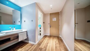 A modern bathroom with a wooden vanity, a large mirror, and a blue accent wall.
