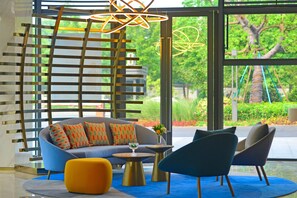 Un interior moderno con un sofá, sillas, una mesa de centro y una lámpara decorativa.
