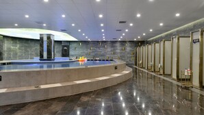 A modern indoor swimming pool with a curved design, surrounded by a marble floor and walls, and equipped with multiple changing rooms and a reception area. - Mercure Taiyuan Jinyang (Taiyuan)