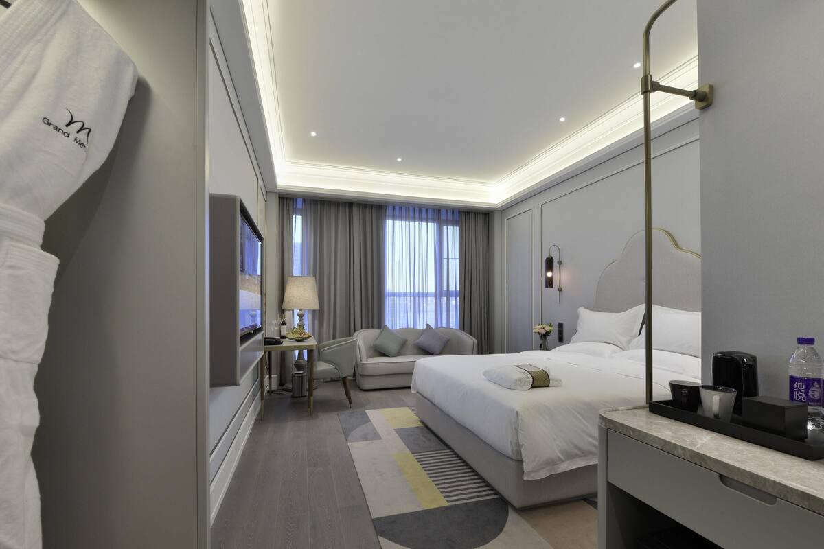 Une chambre d’hôtel moderne équipée d’un grand lit, d’un bureau, d’une chaise, d’une télévision et d’une salle de bain.