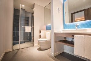 Une salle de bain moderne avec une douche à parois de verre, des toilettes et un lavabo avec un miroir au-dessus.
