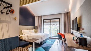 A modern hotel room with a bed, a desk, a chair, a TV, and a window with curtains. - Holiday Inn Express Guizhou Qinglong by IHG (Qianxinan Buyei and Miao)