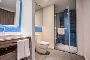Ein modernes Badezimmer mit Toilette, einer Duschkabine und einem Waschtisch mit Spiegel und Waschbecken.