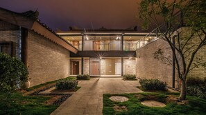 Un patio con un edificio tradicional, un corredor cubierto y un jardín bien cuidado.