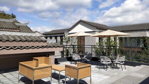 A rooftop patio with outdoor seating, including wooden and metal chairs, and a table. - Holiday Inn Express Guizhou Qinglong by IHG (Qianxinan Buyei and Miao)