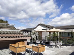 Une terrasse sur le toit avec des espaces de détente en plein air, comprenant des chaises en bois et en métal, ainsi qu’une table.