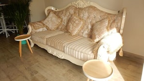 Un canapé beige agrémenté de motifs décoratifs et un fauteuil assorti, dans une pièce dont le sol est recouvert de parquet.