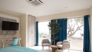 Une chambre d’hôtel moderne équipée d’un grand lit, d’un bureau, d’une chaise, d’une petite table et d’un téléviseur fixé au mur.