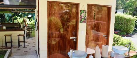 A bathroom with a wooden vanity, a glass bowl sink, and a mirror. There are two doors, one labeled "Damas" and the other "Caleforni."
