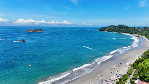 A coastal beach with clear blue waters, a sandy shore, and a lush green hillside. - Hotel Playa Espadilla  (Quepos)