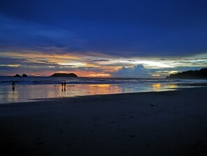 A beach with a sunset, calm waters, and a distant island. - Hotel Playa Espadilla  (Quepos)
