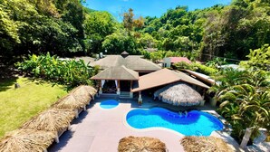 A resort with a swimming pool, thatched-roof structures, and lush greenery. - Hotel Playa Espadilla  (Quepos)