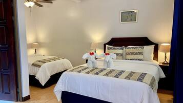 A hotel room with two beds, a ceiling fan, a nightstand with lamps, and a framed picture on the wall.