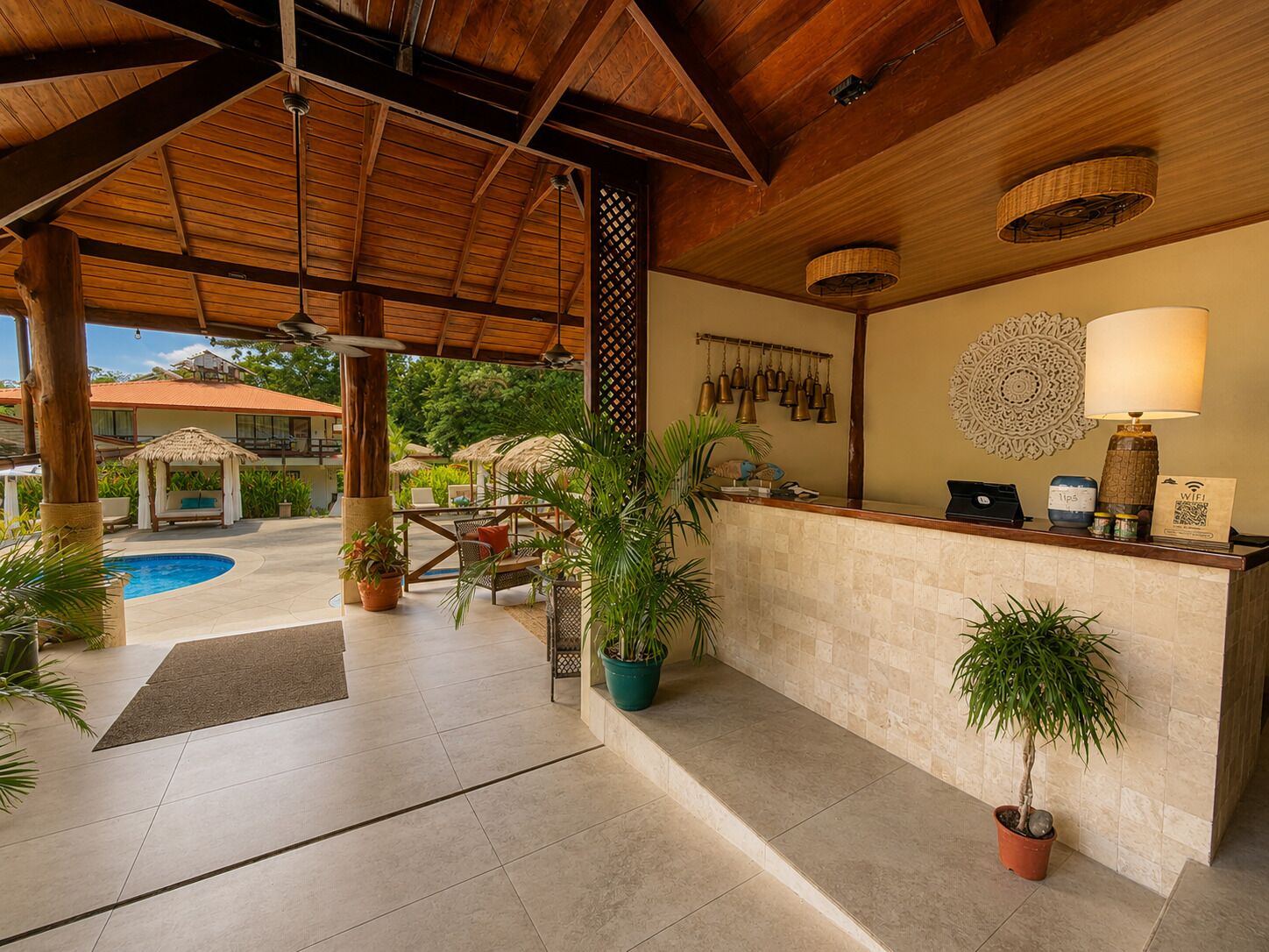 Un área de recepción con piscina, plantas en macetas y techo de madera.