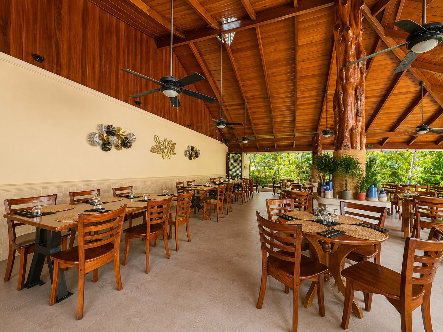 A spacious indoor dining area with wooden tables and chairs, ceiling fans, and decorative wall art.