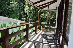 A balcony with a wooden railing, a round metal table, and chairs. There is a potted plant on the balcony. - Hotel Playa Espadilla  (Quepos)