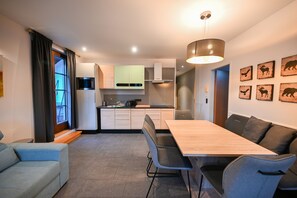 A modern kitchen with a dining area, a sofa, and a table.