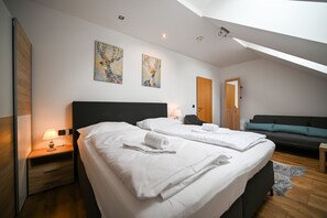 A modern hotel room with two beds, a sofa, and artwork on the walls.