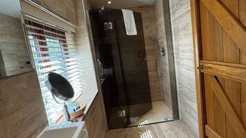 A modern bathroom with a large bathtub, a shower area, and a wooden door.