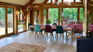 Un comedor con vigas de madera, ventanas amplias y un rústico hogar.