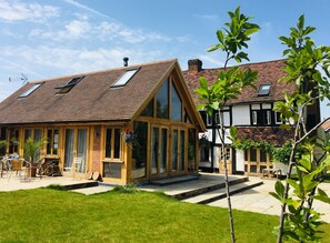 A two-story house with a sloped roof, large windows, and a visible chimney. - Heathrow Cottages B&B (Staines)