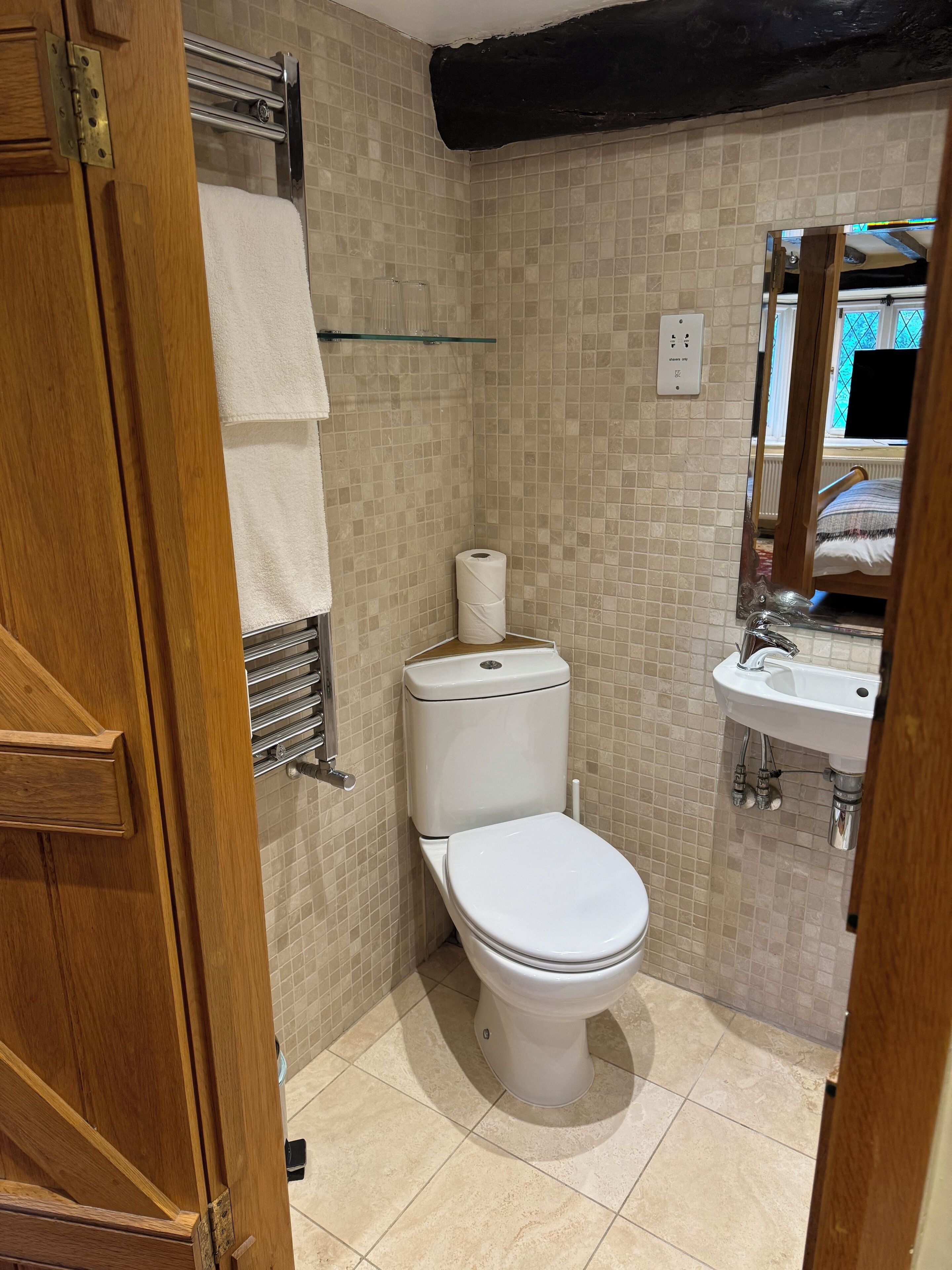 Un baño con inodoro, lavamanos y perchero para toallas.