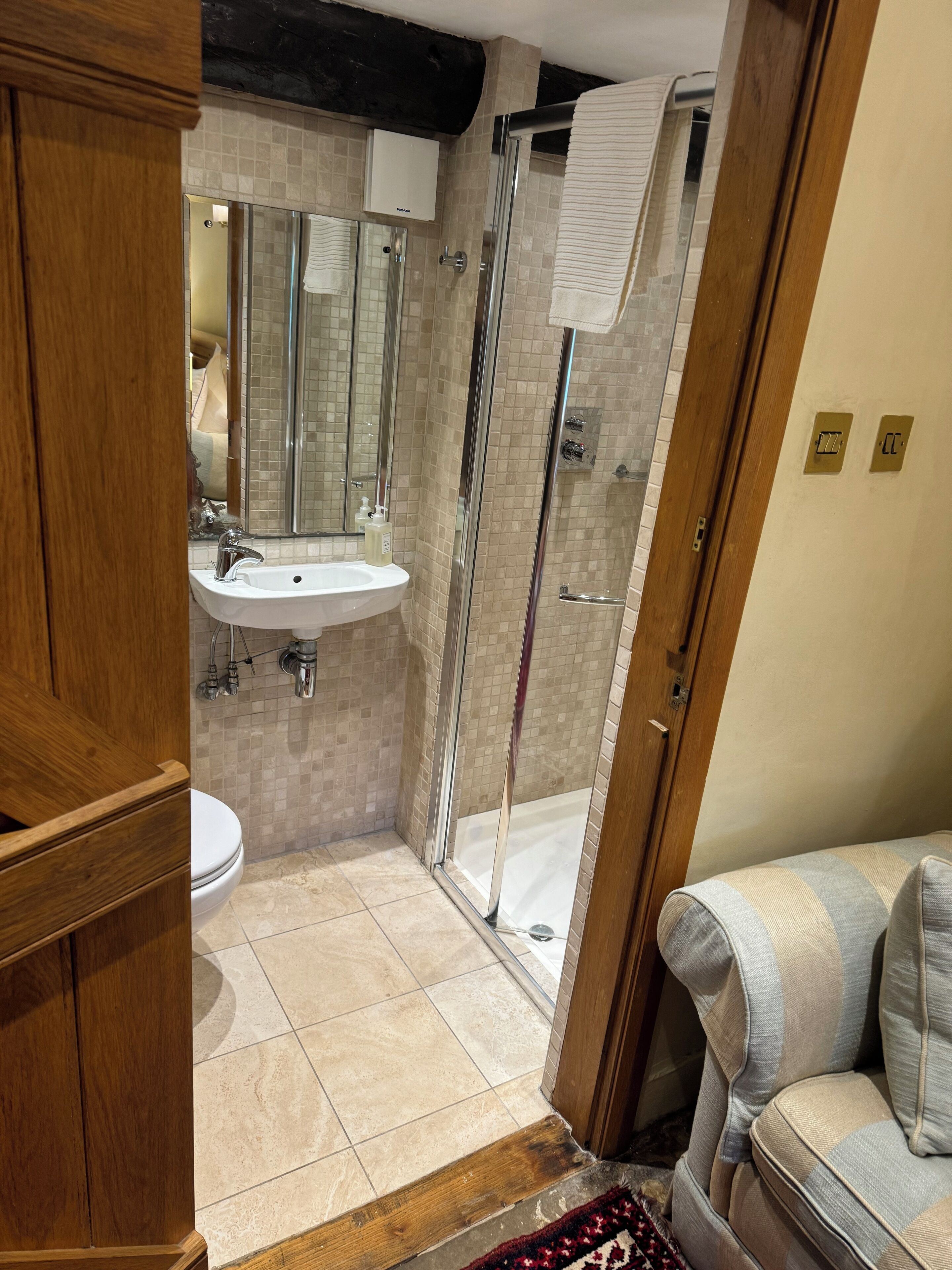 A bathroom with a glass-enclosed shower, a sink, and a toilet.