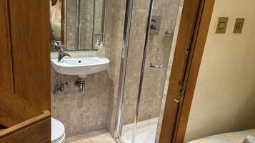 A bathroom with a glass-enclosed shower, a sink, and a toilet.