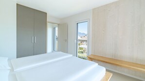 Un dormitorio moderno con una cama grande, un armario y un ventanal corredero que da a un balcón.