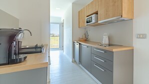 Una cocina moderna con armarios grises, encimera de madera, microondas integrado y cafetera.