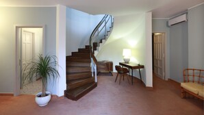 A staircase leading to an upper floor, a potted plant, a table with a lamp, and a wicker chair. - Dimora Villa Serena Porto Selvaggio (Nardò)